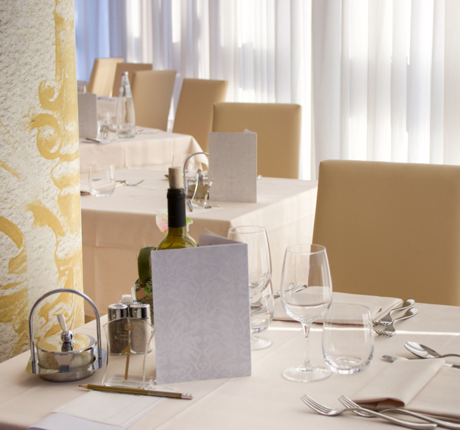 Ristorante elegante con tavoli apparecchiati e luce naturale.