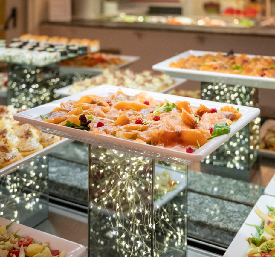 Buffet elegante con piatti di antipasti e luci decorative.